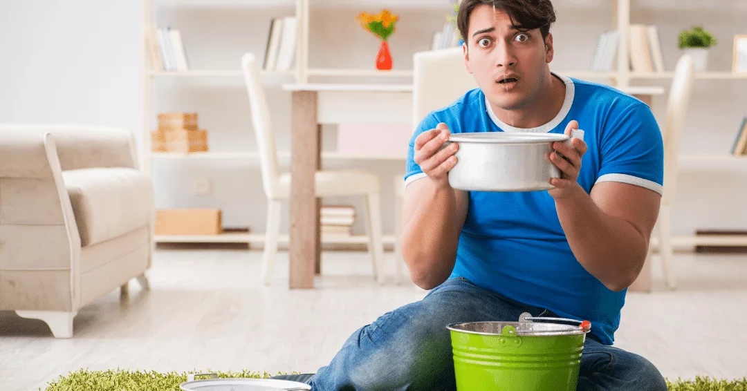 man dealing with leaky roof catching water in bowl