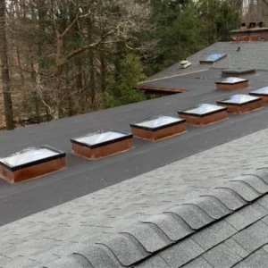 flat roof repair on roof with many skylights that have copper flashing around them