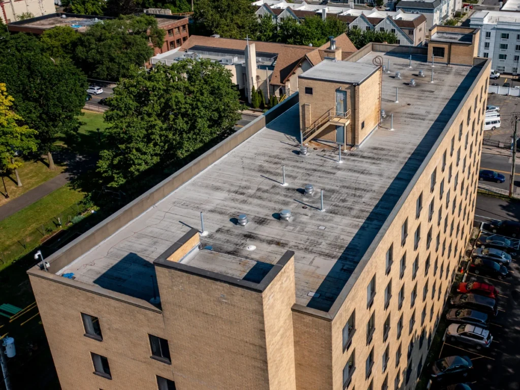 side aerial view of a discolored flat roof on residential building in new rochelle, NY