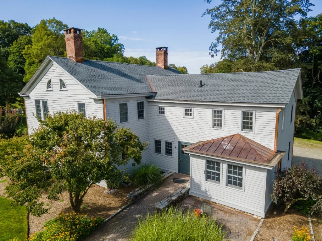 rear of house showing light grey GAF shingle roof installation with a custom copper lower roof in somers, ny