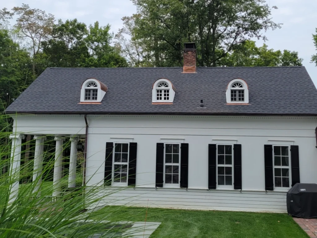 after roof replacement showing new grey asphalt roof shingles with copper window dormers and copper flashing