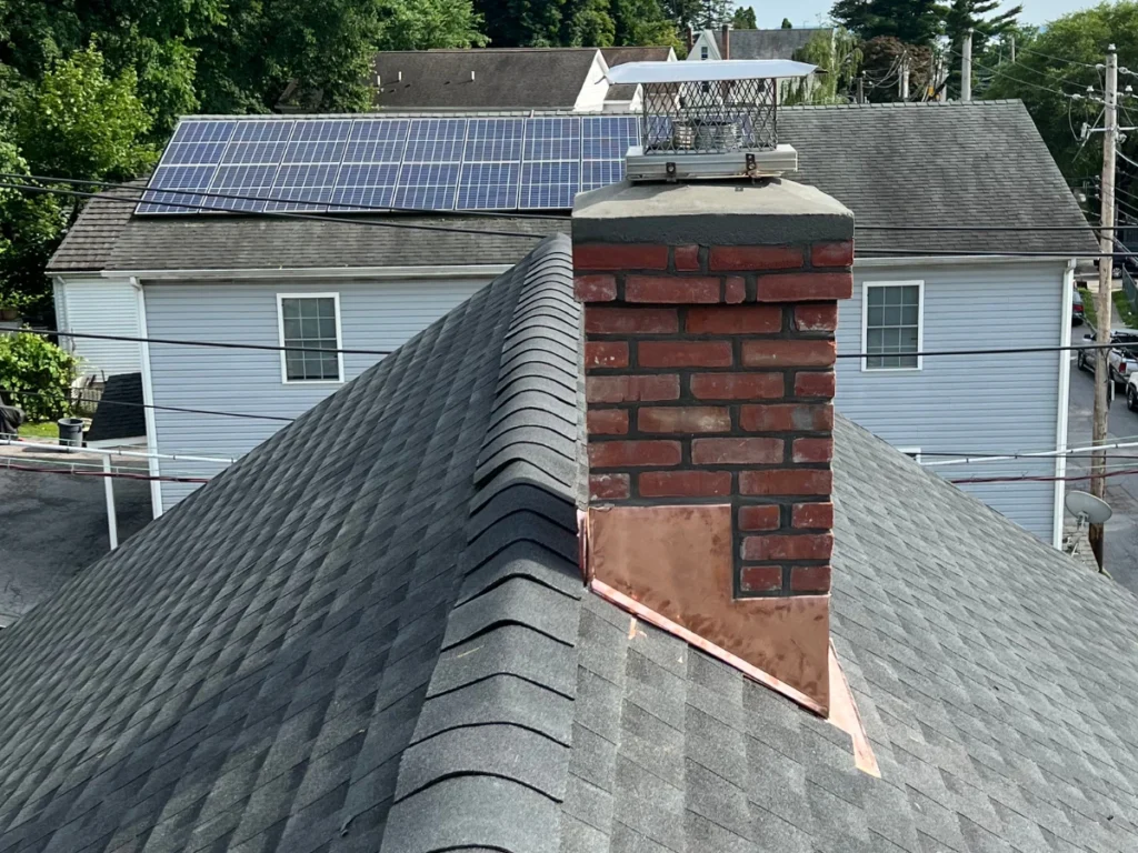 close up of a new shingle roof and chimney rebuilt with copper lashing