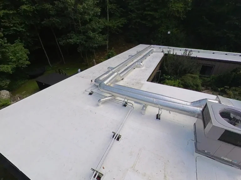 White flat commercial roof with HVAC unit and piping near Armonk