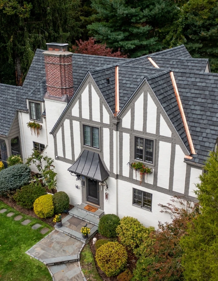 Tudor-style home with dark gray architectural shingle roof and copper accents near Armonk