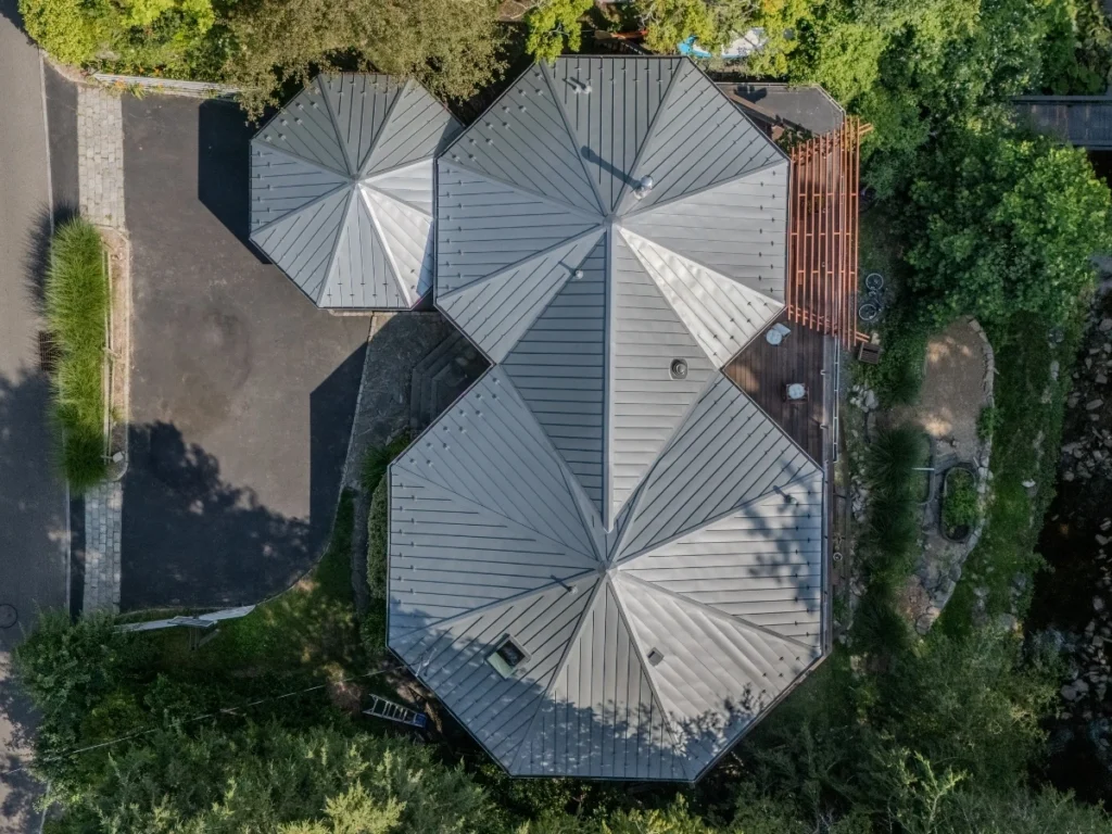 Overhead view of a modern home with a metal panel roof featuring multiple pitched sections.