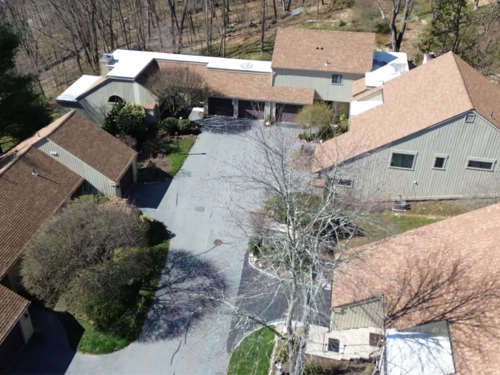 Townhomes with new CertainTeed brown shingle roofs and some flat white roof sections.